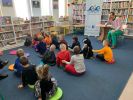 Zdjęcie przedstawia grupę dzieci i osobę dorosłą w Bibliotece.