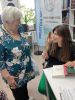 Zdjęcie przedstawia ludzi w bibliotece na spotkaniu autorskim
