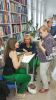 Zdjęcie przedstawia ludzi w bibliotece na spotkaniu autorskim