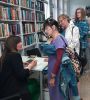 Zdjęcie przedstawia ludzi w bibliotece na spotkaniu autorskim