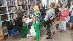 Zdjęcie przedstawia ludzi w bibliotece na spotkaniu autorskim
