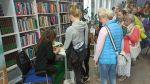 Zdjęcie przedstawia ludzi w bibliotece na spotkaniu autorskim