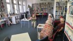 Zdjęcie przedstawia ludzi w bibliotece
