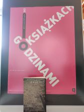 Zdjęcie przedstawia plakat z haslem Godzinami o ksiazkach oraz ksiazka pt Rejwach Mikolaja Grynberga