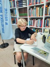 Ludzie w bibliotece podczas spotkania autorskiego