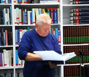 Zdjęcie przedstawia czlowieka podpisujacego ksiazke