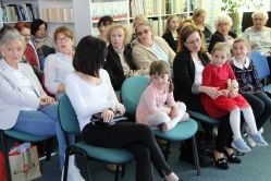 Grupa ludzi siedzi na krzesłach w bibliotece