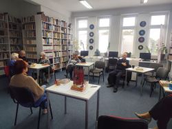 Zdjęcie przedstawia ludzi w bibliotece