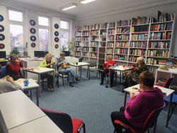 Zdjęcie przedstawia ludzi w bibliotece