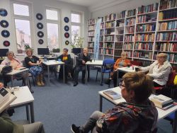 Zdjęcie przedstawia ludzi w bibliotece