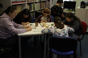 Zdjęcie przedstawia ludzi w bibliotece