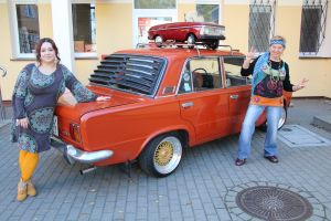 Zdjęcie przedstawia dwie osoby stojące przy dużym fiacie