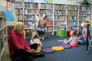 zdjęcie przedstawia dzieci i panią bibliotekarkę czytającą wiersze Juliana Tuwima