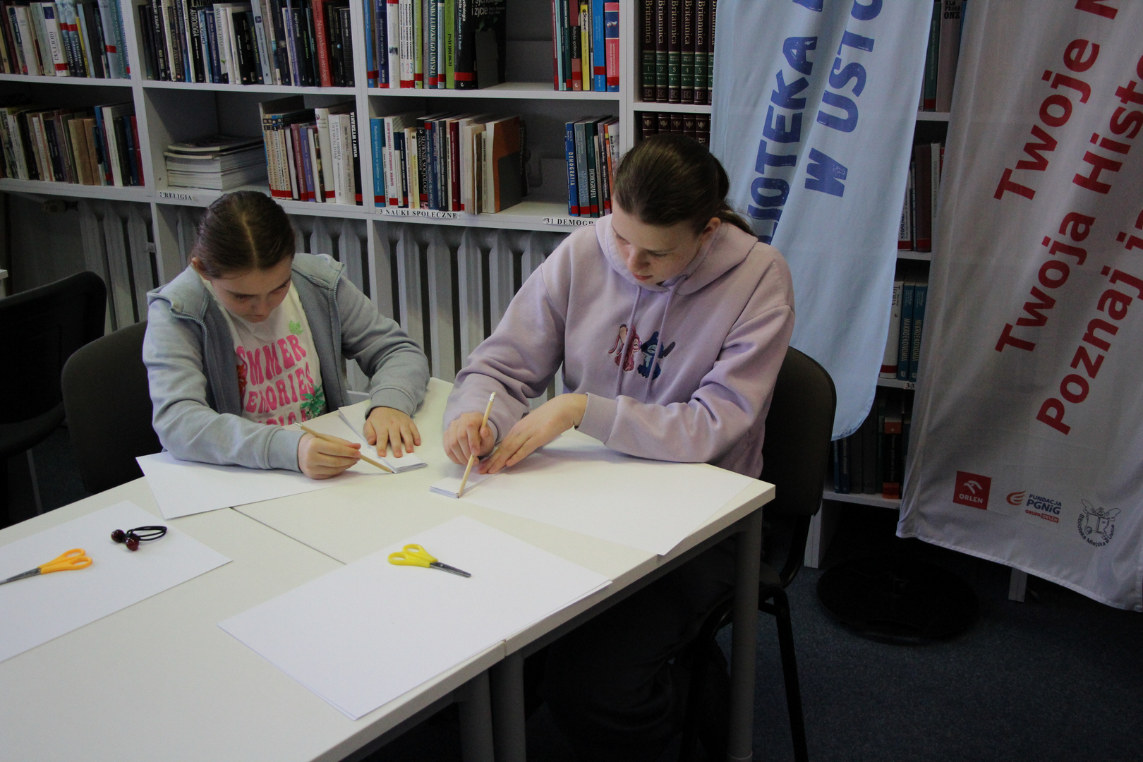 Zdjęcie przedstawia ludzi w bibliotece