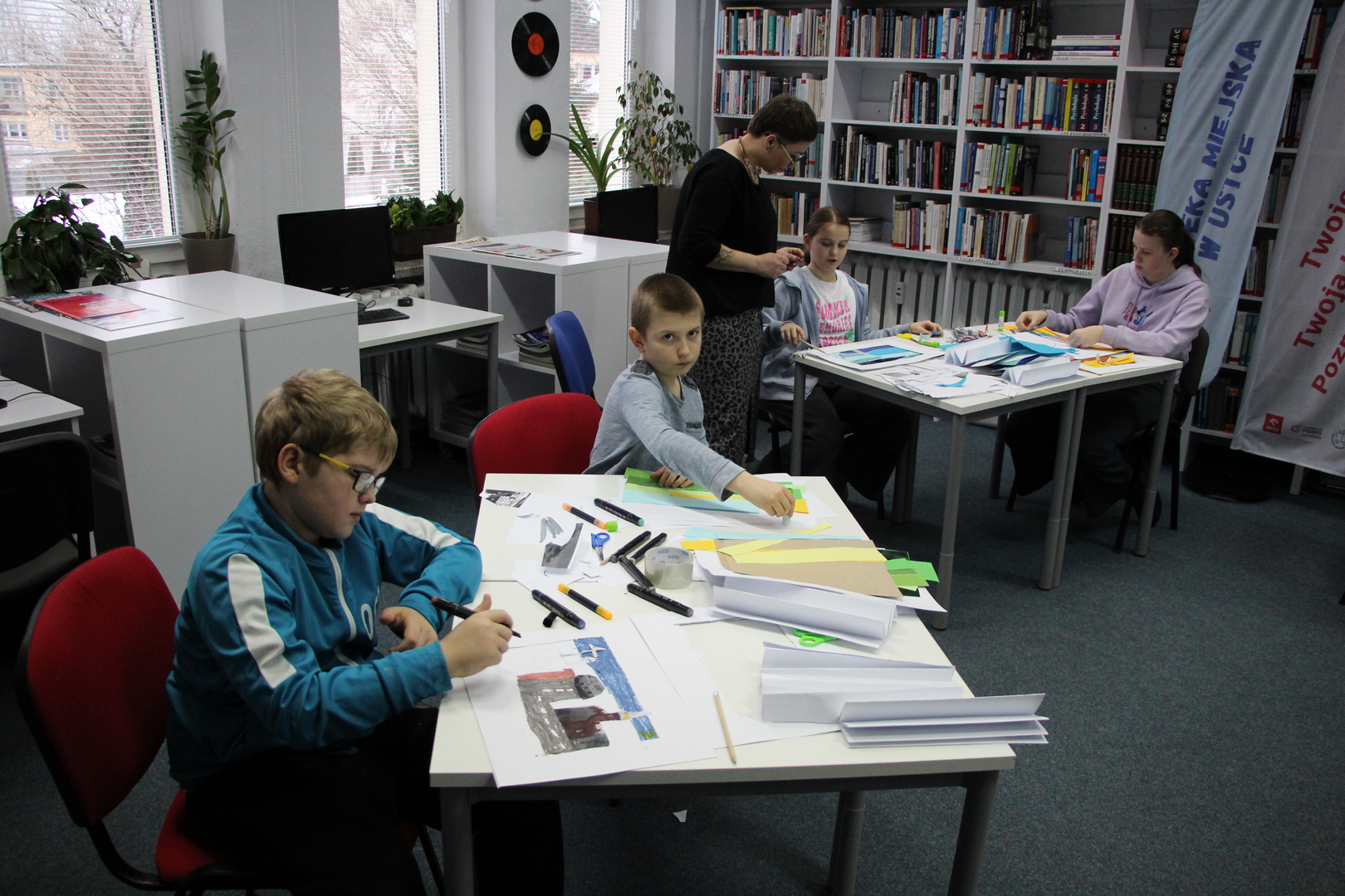 Zdjęcie przedstawia ludzi w bibliotece