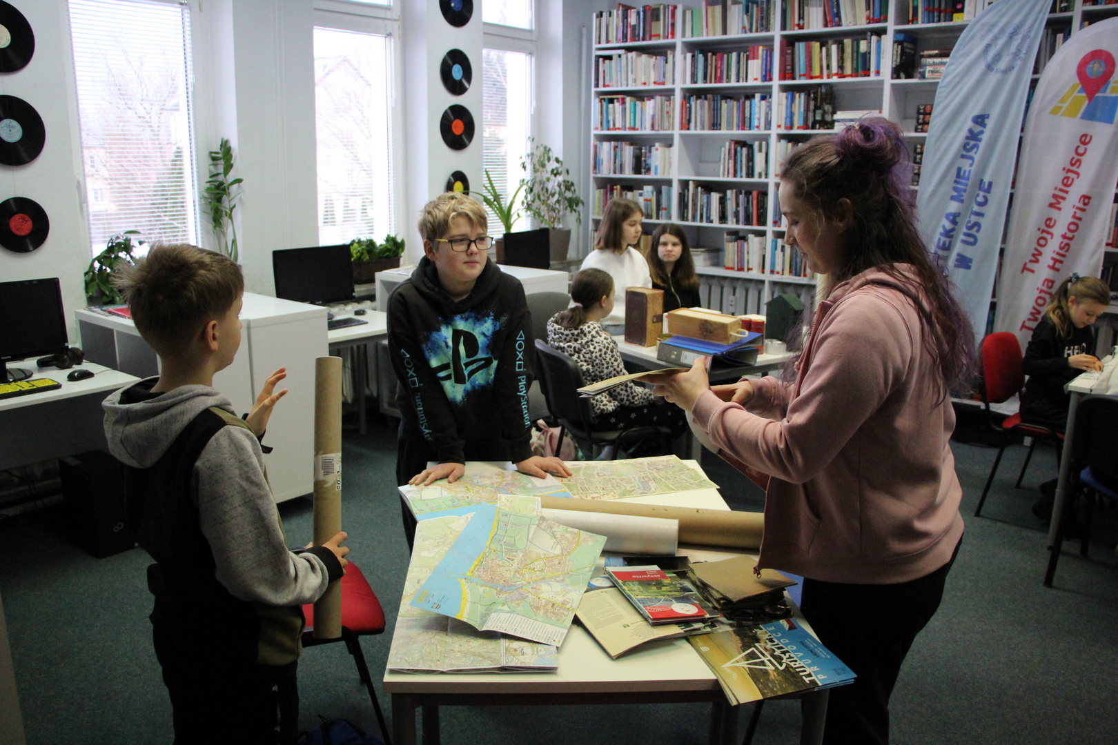 Zdjęcie przedstawia ludzi w bibliotece