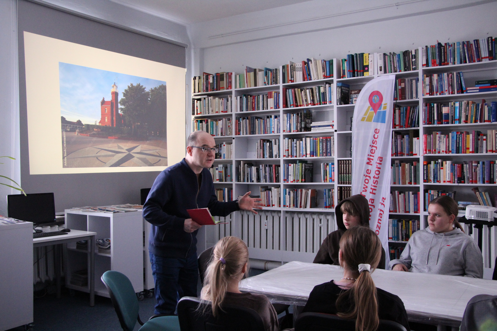 Zdjęcie przedstawia ludzi w bibliotece