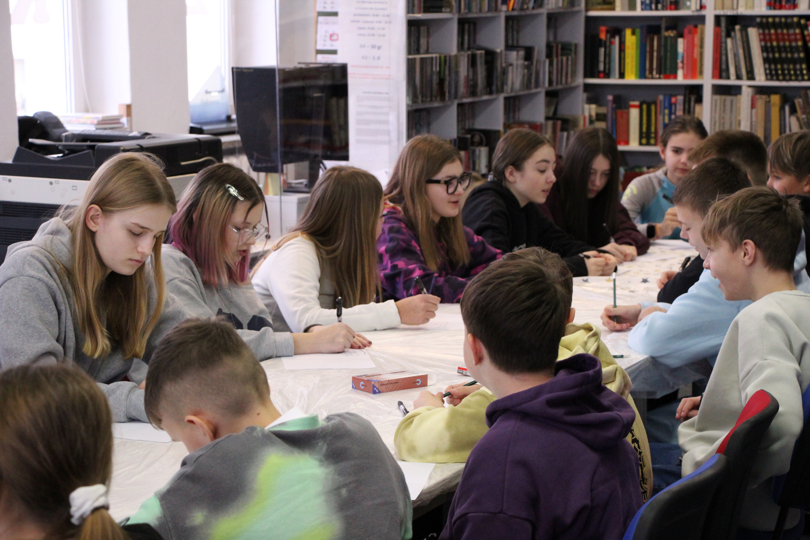 Zdjęcie przedstawia ludzi w bibliotece