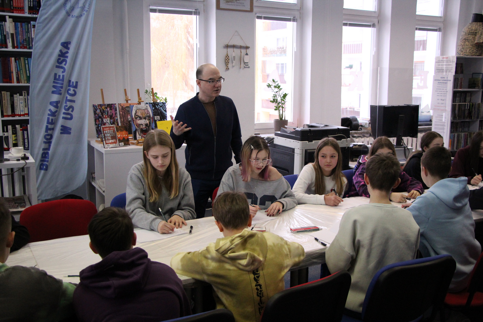 Zdjęcie przedstawia ludzi w bibliotece